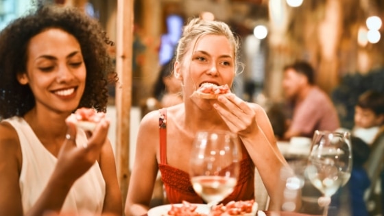 two women eating dinner and drinking wine on a night out