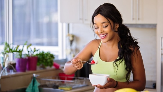woman eating a healthy fruit bowl in a kitchen