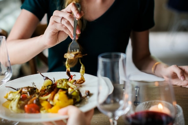 woman at the table eating some healthy food with a glass of red wine