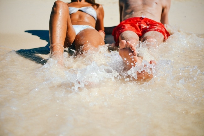 fit woman and man on a beach as the waves come in